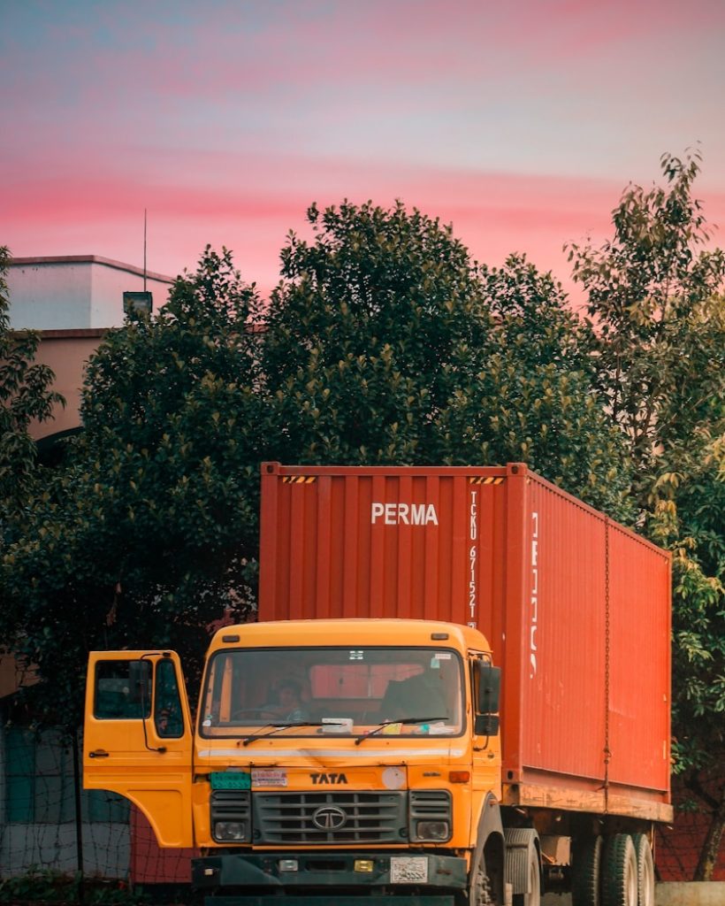 yellow truck parked beside green tree during daytime